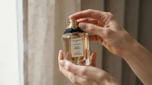 A woman holding a light daily scent bottle as part of her morning workspace routine.